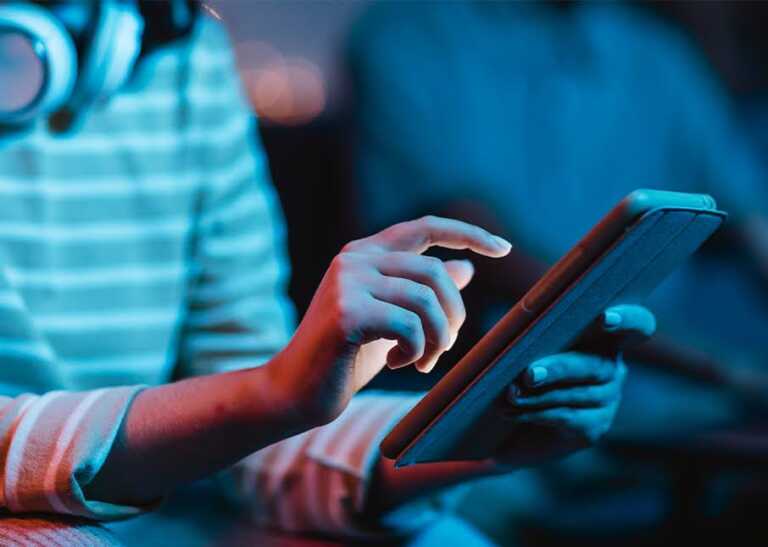 Young Person Using a Super App on a Tablet in Low Light