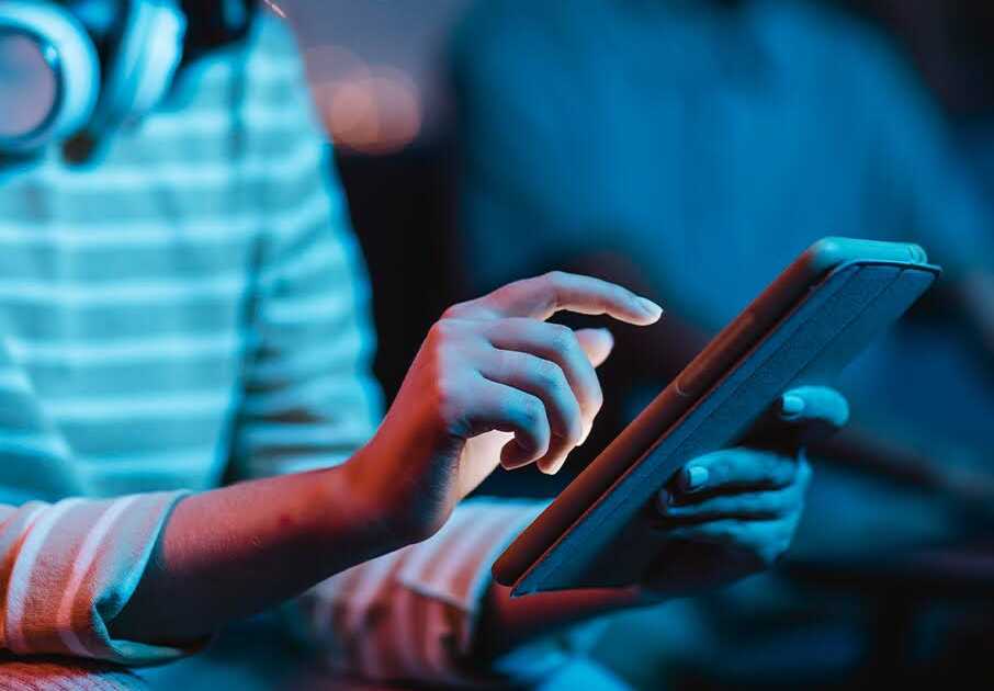 Young Person Using a Super App on a Tablet in Low Light